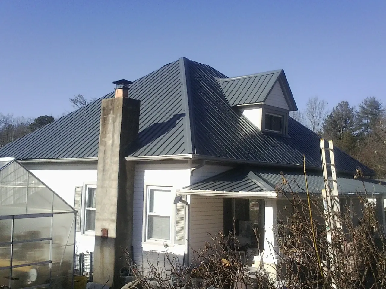 Dark blue standing seam metal roof on a white farmhouse with dormer — Slate & Tile Roof Repair by Roofing Brothers in East Peoria
