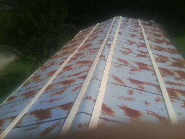 Rusted metal roof panels with new wood purlins before replacement — Storm Damage Roof Repair in East Peoria by Roofing Brothers