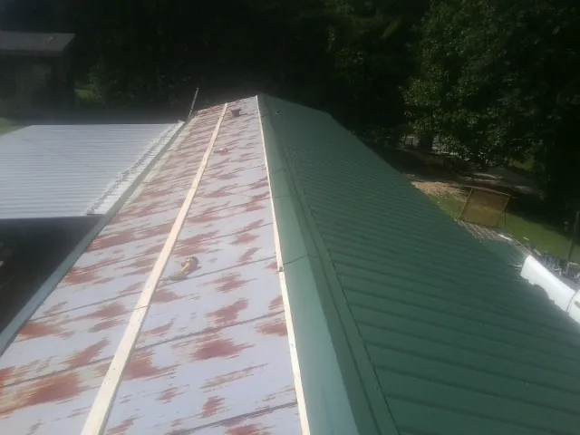 Old rusted panels beside newly installed green metal roofing — Wind Damage Roof Repair by Roofing Brothers in East Peoria