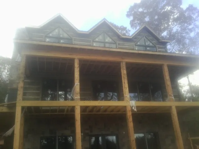 Dormers and porch framing on a large log home under construction — Roof Coating work by our crew in East Peoria