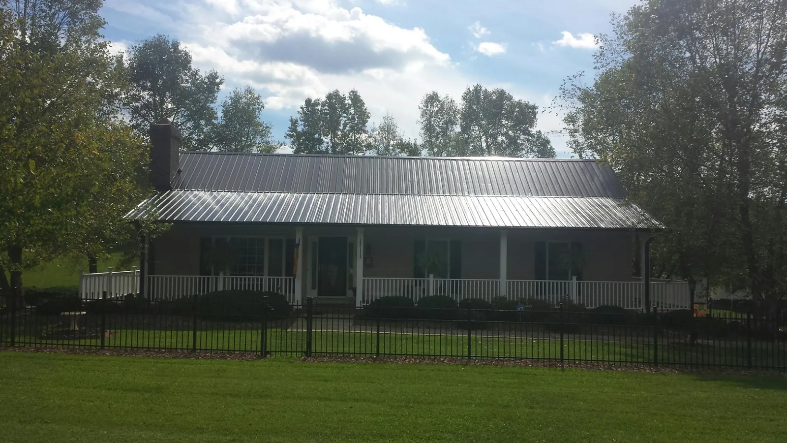 Gray metal roof on a brick ranch with a full width front porch — Gutter Guard Installation work by our crew in East Peoria