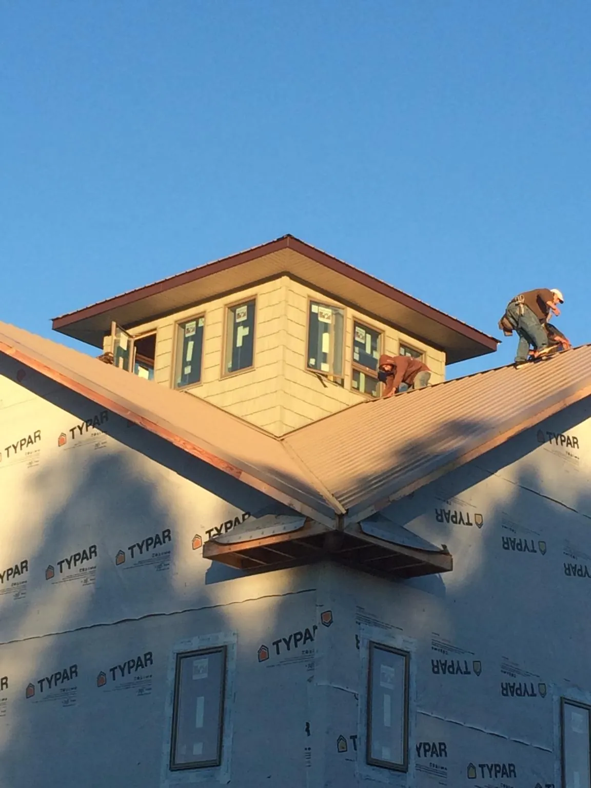 Roofers working around a rooftop cupola on a new metal roof at sunset — Roof Waterproofing in East Peoria by Roofing Brothers